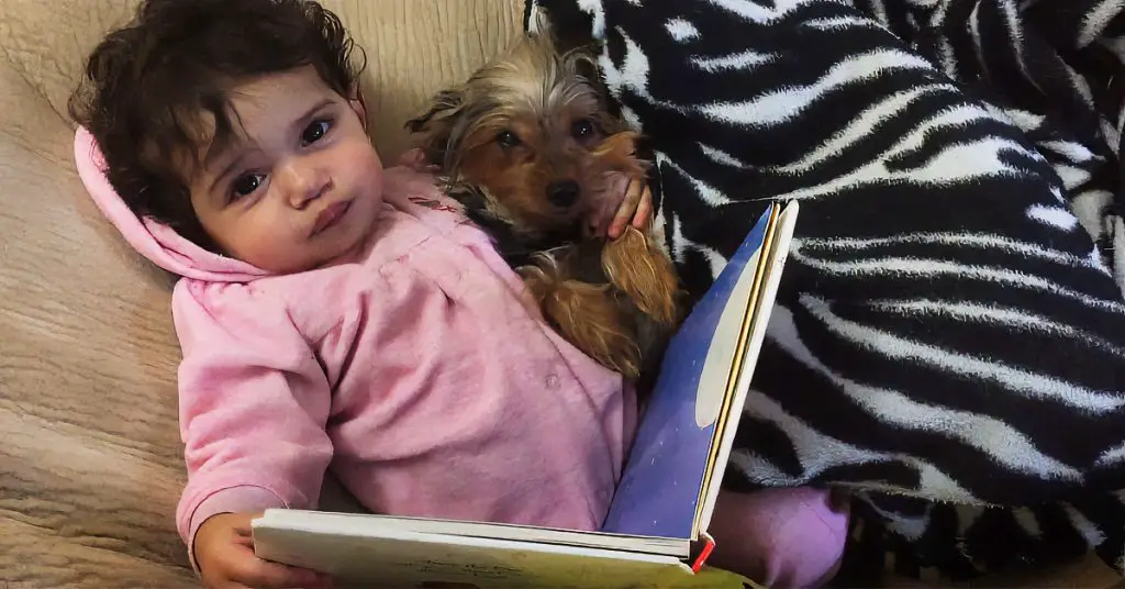 girl reads book to dog